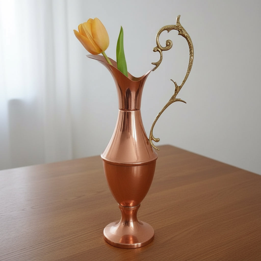 Copper pitcher with a decorative handle on a white background at French Originals antiques