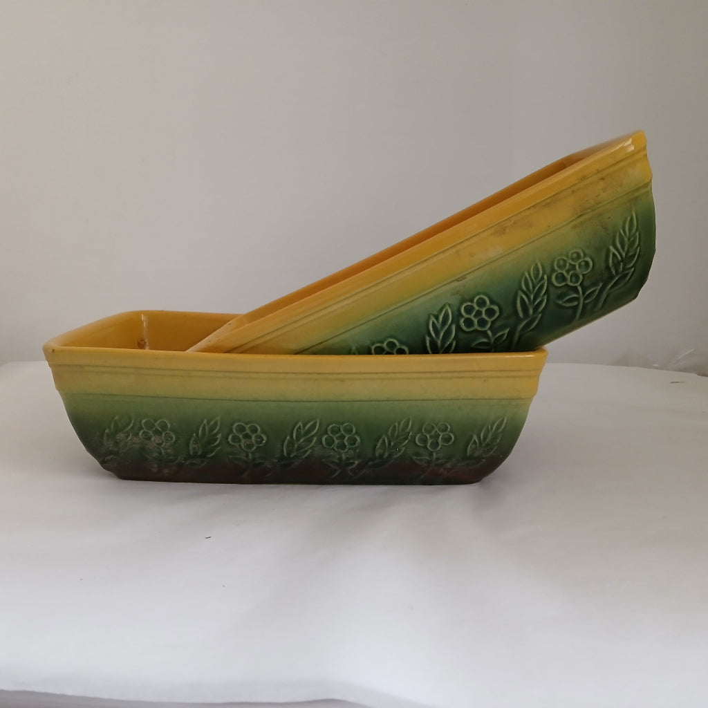 Two green and yellow baking dishes on white table at French Originals antiques
